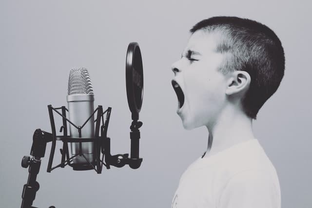 Black and white picture of a boy shouting into a microphone
