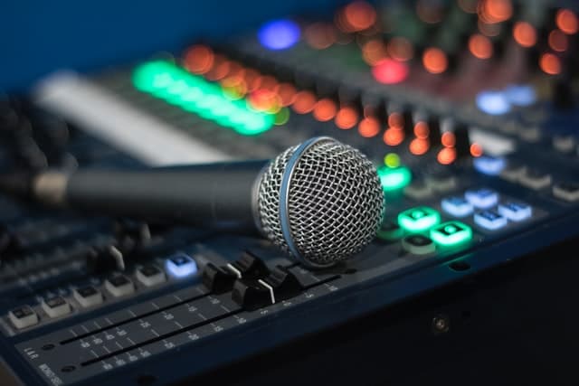 Microphone resting on a a mixing desk with colourful lights